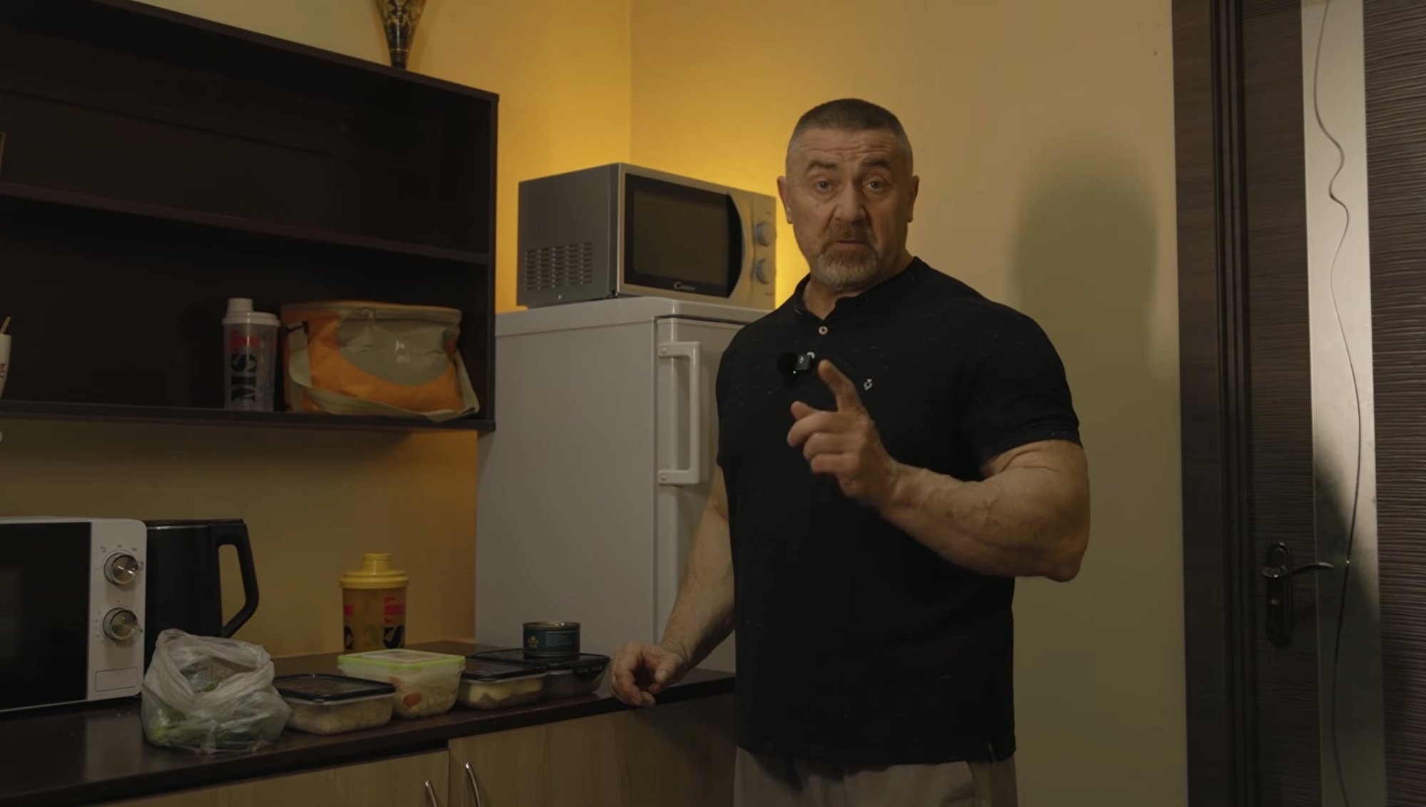 Сергій Яцюк на кухні поруч із контейнерами з їжею, тунцем і шейкером